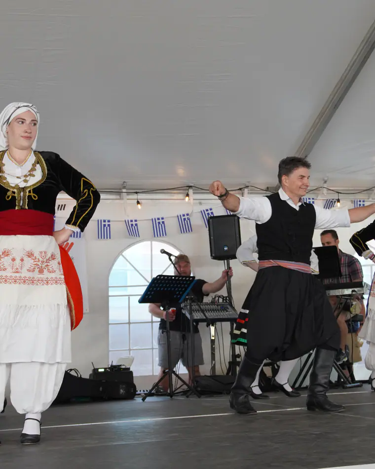 Dancers in traditional dress mid-step on stage