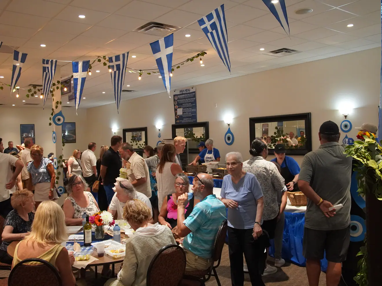 Guests filling the festival hall, decorated with Greek flags and bunting