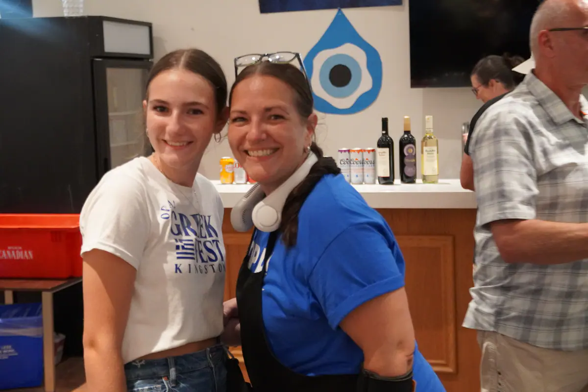 Two Greek Fest volunteers smiling behind the counter